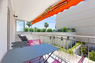 a balcony with a blue table and pink chairs at Modern apartment 2 bedrooms1 bathroom quiet terrace in a palm beach area in Cannes