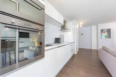 a kitchen and living room with white cabinets and a couch at Modern apartment 2 bedrooms1 bathroom quiet terrace in a palm beach area in Cannes