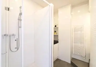 a white bathroom with a shower and a glass door at Lovely and Modern 1 Bedroom City Centre Cannes in Cannes