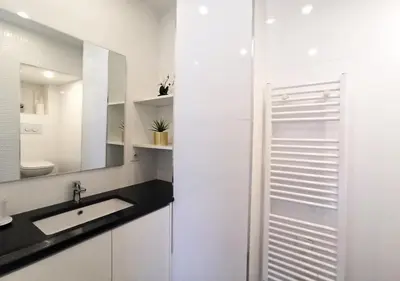 a white bathroom with a sink and a mirror at Lovely and Modern 1 Bedroom City Centre Cannes in Cannes