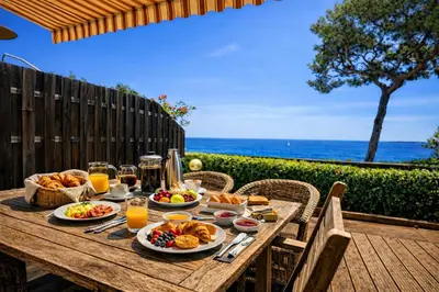 a wooden table with food and drinks and the ocean at Villa Cannes I Deluxe Seafront - Sea View - Garden & Terrace -Prime Location- in Cannes
