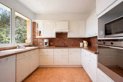 a white kitchen with white cabinets and a window at Villa Cannes I Deluxe Seafront - Sea View - Garden & Terrace -Prime Location- in Cannes
