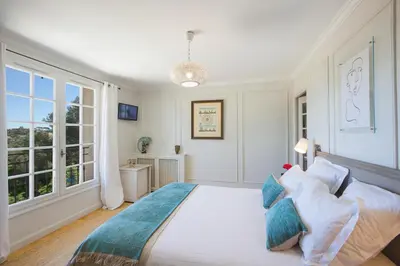 a bedroom with a large bed with blue pillows at Villa Le Port d'attache in Vallauris