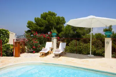 a swimming pool with two chairs and an umbrella at Villa Le Port d'attache in Vallauris