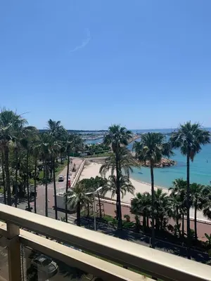 a view of a beach and palm trees from a balcony at Ô Béatrice Croisette in Cannes