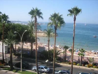a view of a beach with palm trees and the ocean at Ô Béatrice Croisette in Cannes