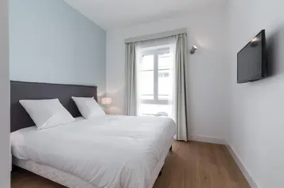 a bedroom with a white bed and a television at Florella Antibes Apartment in Cannes
