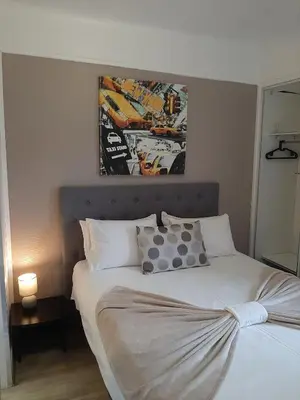 a bedroom with a white bed with a painting above it at Hôtel Bellevue Cannes in Cannes