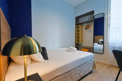 a small bedroom with a bed and a lamp at Hotel Albert 1er in Cannes