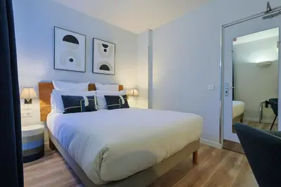 a bedroom with a large white bed with blue pillows at Hotel Albert 1er in Cannes