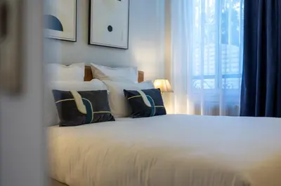 a bedroom with a white bed with pillows and a window at Hotel Albert 1er in Cannes