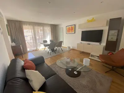 a living room with a black couch and a television at Riviera Eden Palace in Cannes