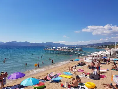 a group of people on a beach with a pier at Chez Grace in Cannes
