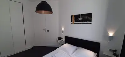 a white bedroom with a bed and a lamp at Cannes Riviera in Cannes