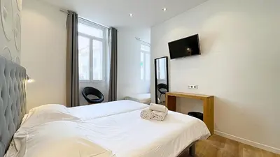 a bedroom with a bed and a tv on the wall at Hotel Le Florian in Cannes