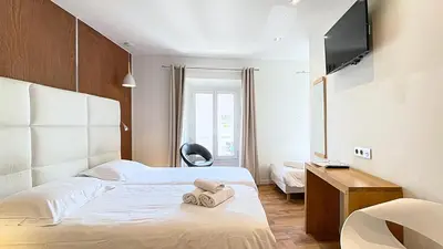 a hotel room with two beds and a flat screen tv at Hotel Le Florian in Cannes