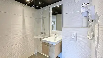 a white bathroom with a sink and a shower at Hotel Le Florian in Cannes