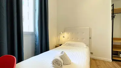 a bedroom with a bed with white sheets and a window at Hotel Le Florian in Cannes