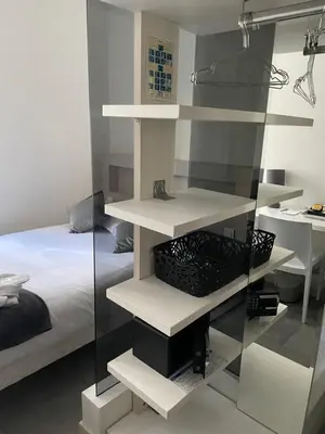 a bedroom with white shelves next to a bed at Hôtel Anna Livia in Cannes