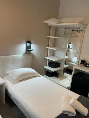 a bedroom with a white bed and shelves at Hôtel Anna Livia in Cannes