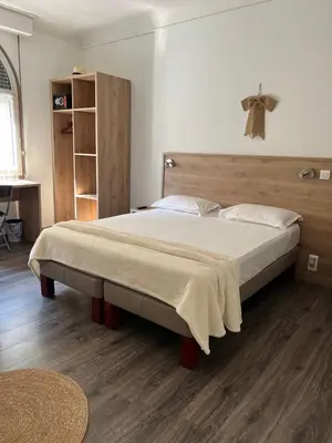 a bedroom with a large bed with a wooden headboard at Hotel Lutetia in Cannes