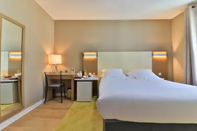 a hotel room with a large bed and a desk at Hotel Amiraute in Cannes