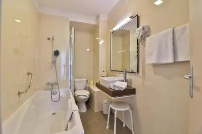 a bathroom with a tub and a toilet and a sink at Hotel Amiraute in Cannes