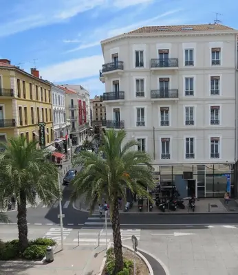 a city street with palm trees in front of a building at Hotel Amiraute in Cannes