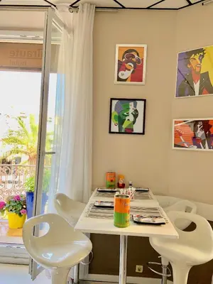 a dining room with a white table and white chairs at Hotel Amiraute in Cannes