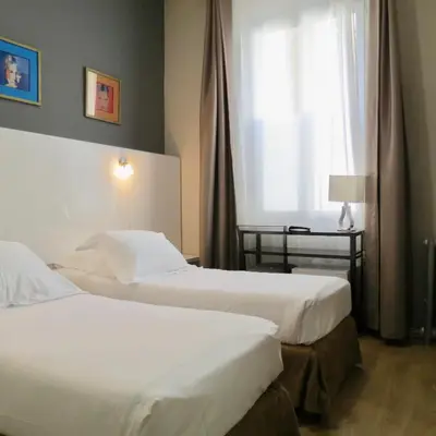 a hotel room with two beds and a window at Hotel Amiraute in Cannes