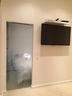 a room with a glass door with a television on the wall at Palme d'hote in Cannes