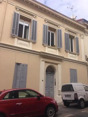 a red car parked in front of a building with blue shutters at Palme d'hote in Cannes