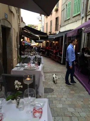 a man and a dog standing in a street with tables at Palme d'hote in Cannes