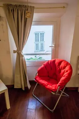 a red chair sitting in front of a window at Le Suquet Style by Connexion in Cannes