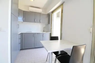 a white kitchen with a table and chairs at 2 bedroom & studio Palais Royal 2 mins from Croisette and Carlton in Cannes