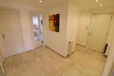 a hallway with white walls and wooden floors and a painting at 2 bedroom & studio Palais Royal 2 mins from Croisette and Carlton in Cannes