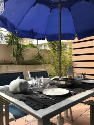 a table with a blue umbrella and plates on it at SOPHIES HOMES FÉLIBRIGES BEACH & PALAIS des FESTIVALS in Cannes
