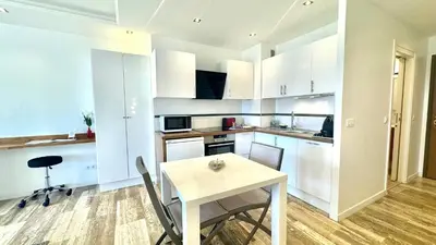a kitchen with white cabinets and a table with chairs at Studio Grand hôtel Croisette, by Welcome to Cannes in Cannes
