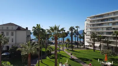 a view of a park with palm trees and a building at Studio Grand hôtel Croisette, by Welcome to Cannes in Cannes