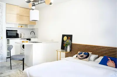a bedroom with a white bed and a kitchen at Majestic Apartment in Cannes