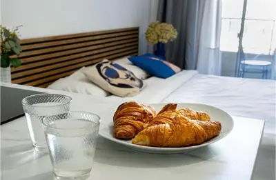 a plate of croissants on a table next to a bed at Majestic Apartment in Cannes