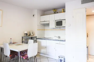a kitchen with white cabinets and a table and chairs at CANNES Palazzio in Cannes