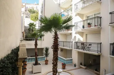 a courtyard with two palm trees in front of a building at CANNES Palazzio in Cannes