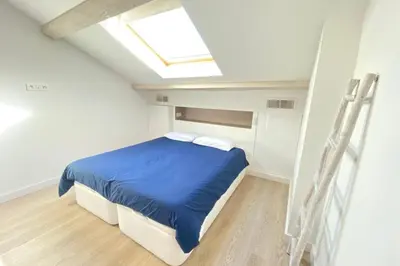 a bedroom with a bed with blue sheets and a skylight at Modern & bright 4-room apartment in Cannes Banane in Cannes