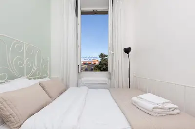 a white bedroom with a bed and a window at Apartment29 in Cannes