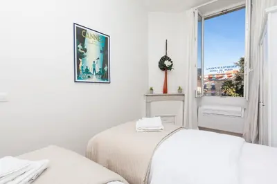 two beds in a white room with a window at Apartment29 in Cannes