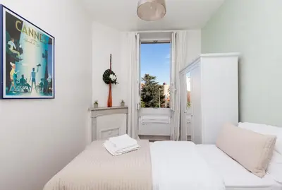 a white bedroom with two beds and a window at Apartment29 in Cannes