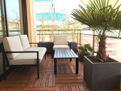 a patio with two chairs and a table and palm trees at Appartement Residence Athena in Cannes