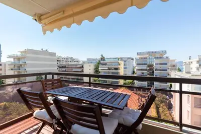 a table and chairs on a balcony with a view of a city at Appartement Residence Athena in Cannes