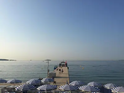a pier with blue and white umbrellas on the water at Immeuble le St Honorat in Cannes